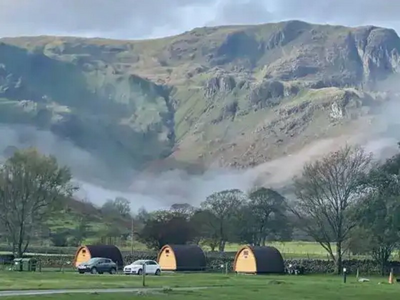 Camping pods at Sykeside with the Lake District fells in the background on a misty morning