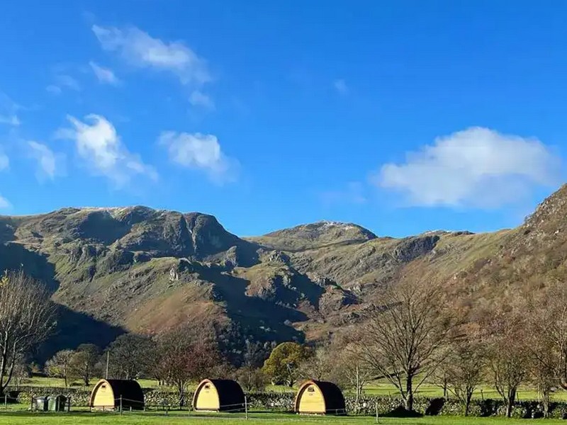 Camping pods at Sykeside with the Lake District fells in the background on a sunny day
